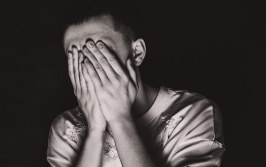 grayscale photo of a man covering his face