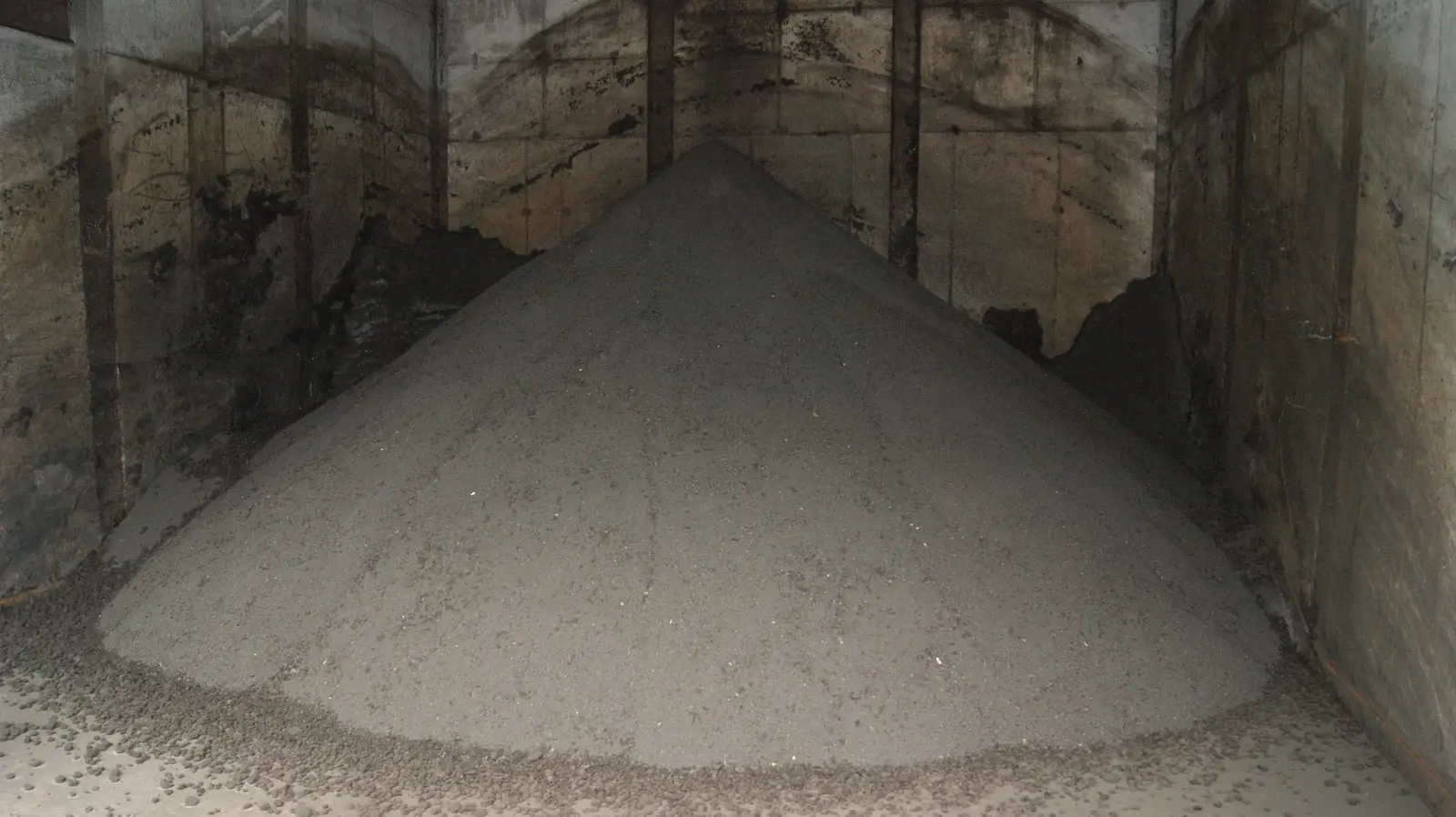 Hrpa sivkasto-smeđih granula osušenog mulja u betonskom skladišnom bunkeru pročistača otpadnih voda u Dornbirnu, Austrija.
