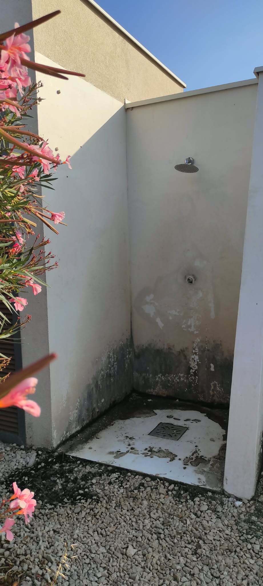 Vanjski tuš s crnom plijesni pri dnu zidova
