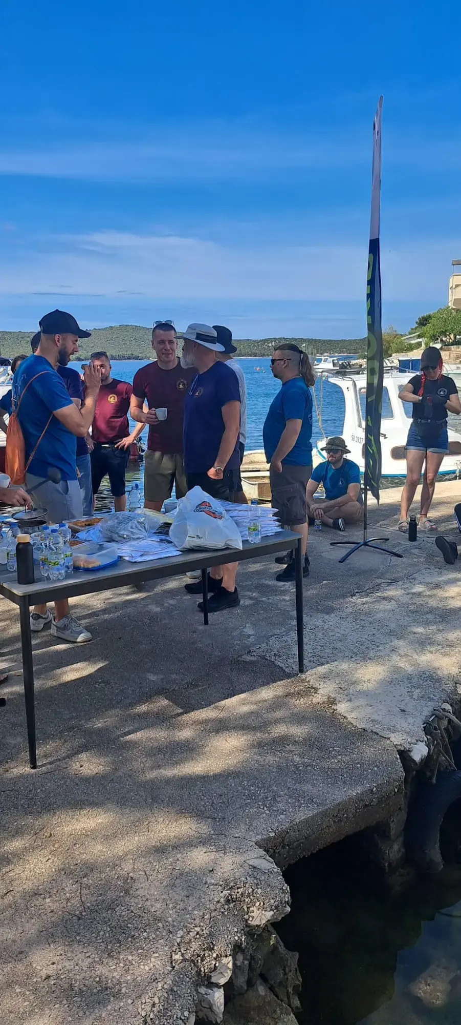 Volonteri okupljeni oko stola s okrjepom na rivi