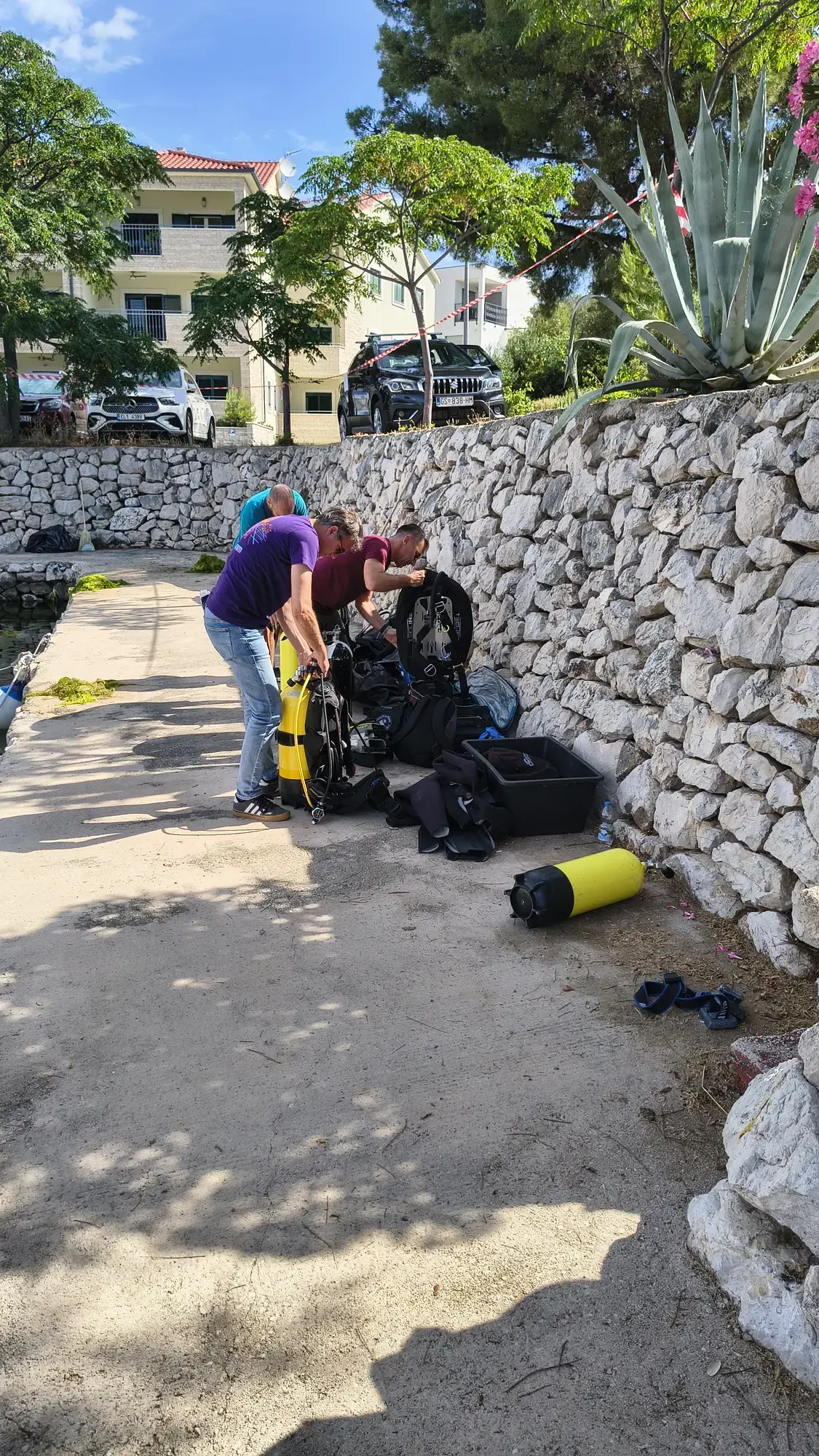 Ronioci pripremaju opremu uz kameni zid na obali