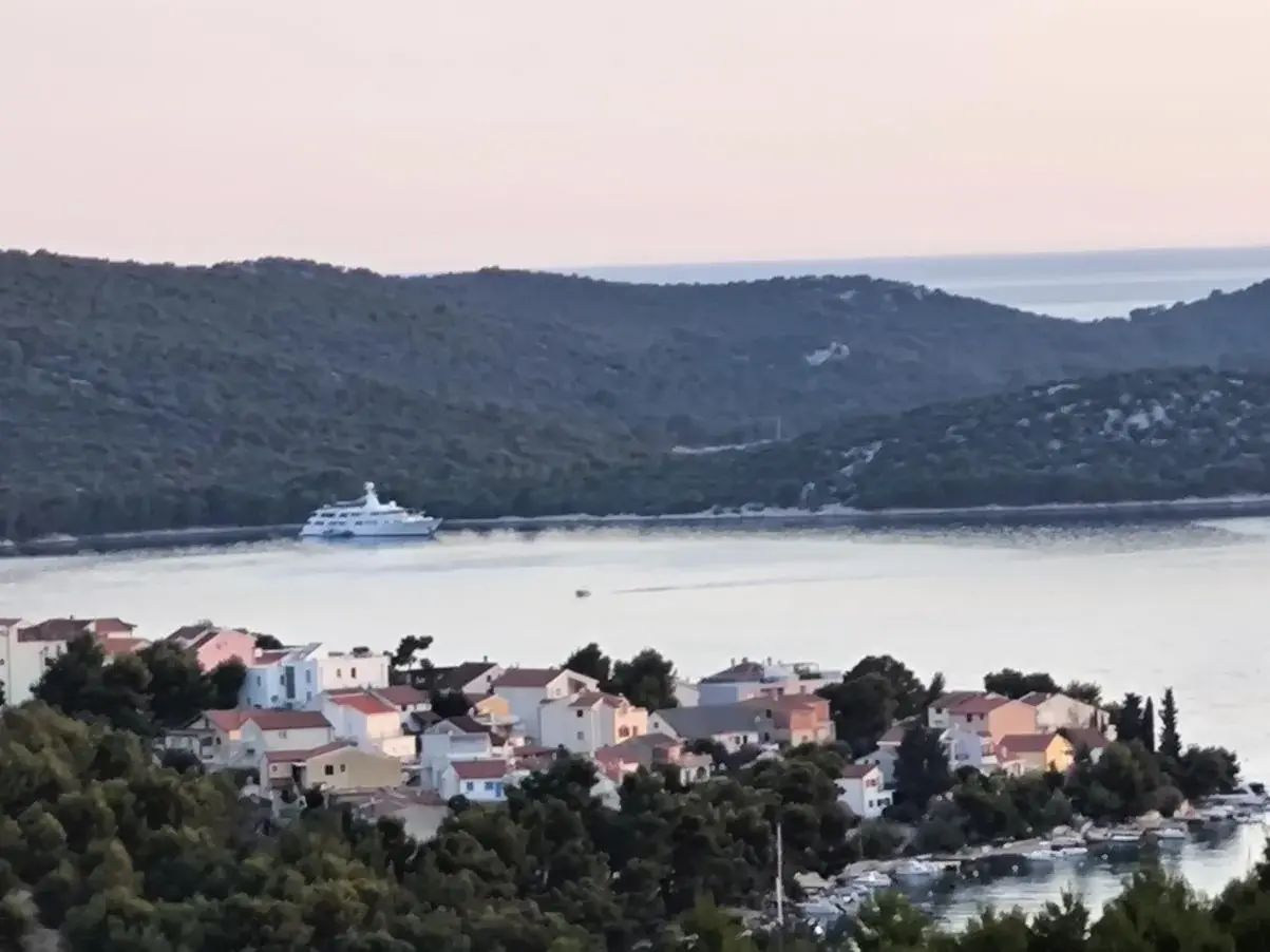 Kruzer usidren uz poluotok Oštricu, u prvom planu kuće Žaborića