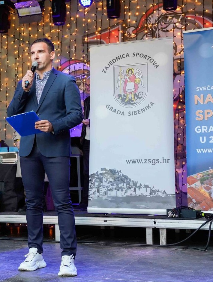 Dario Kulušić govori na pozornici ispred bannera Zajednice sportova