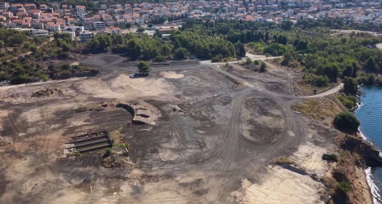 Snimka iz zraka: očišćeni plato bivšeg TEF-a uz more, iza njega borova šuma i naselje