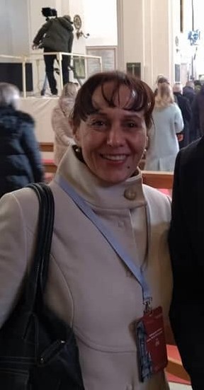 Ljiljana Zmijanović u svijetlom kaputu, s akreditacijom oko vrata, u crkvi