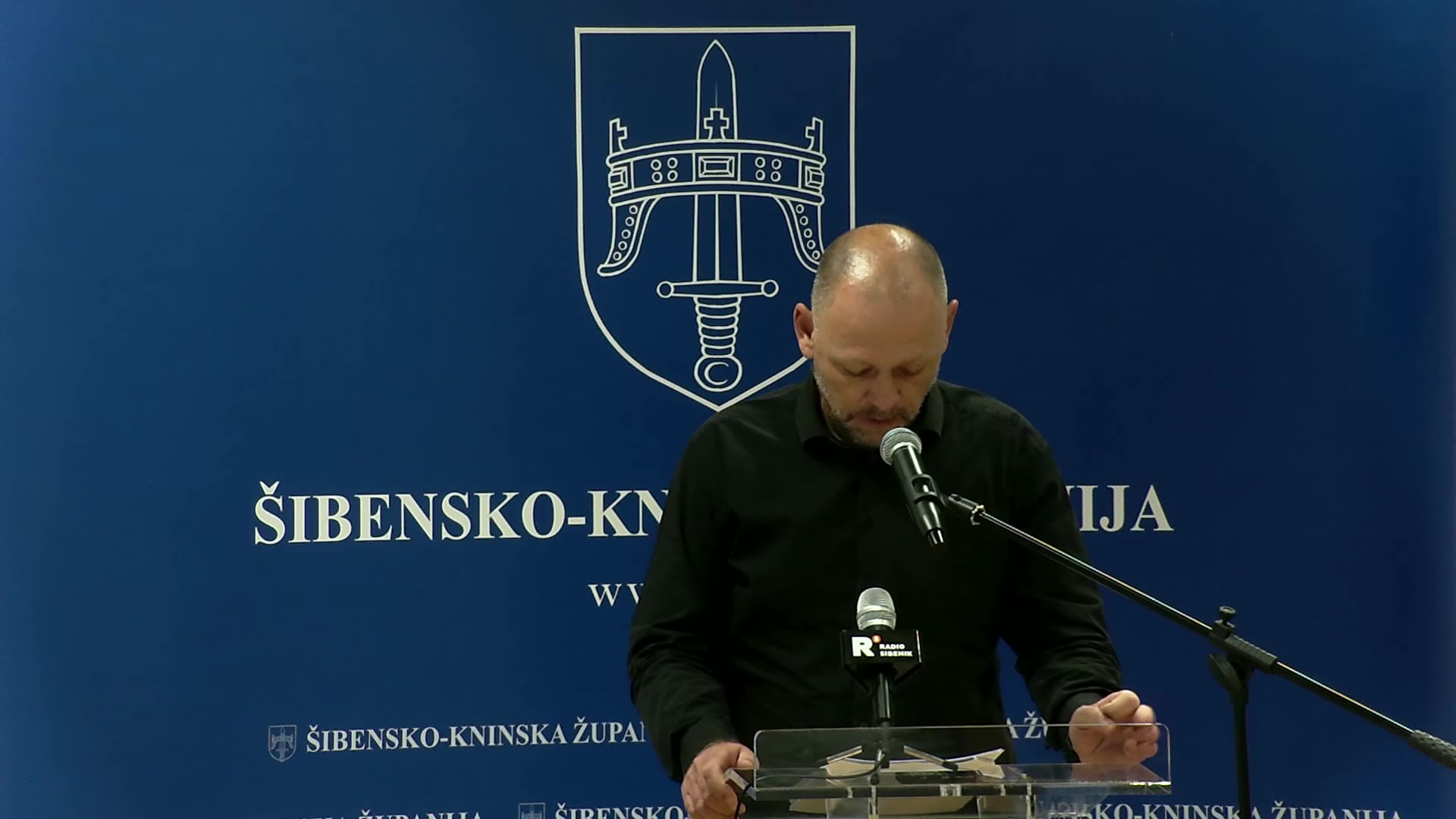 Vijećnik Marko Mačukat govori za govornicom ispred grba Šibensko-kninske županije