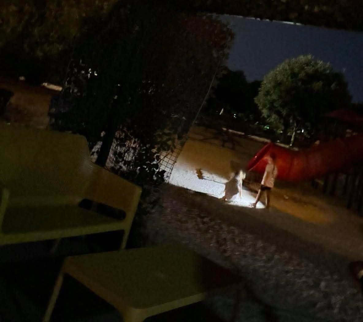 Djeca na neosvijetljenom igralištu, jedini izvor svjetla je baterija mobitela koja osvjetljava krug na tlu