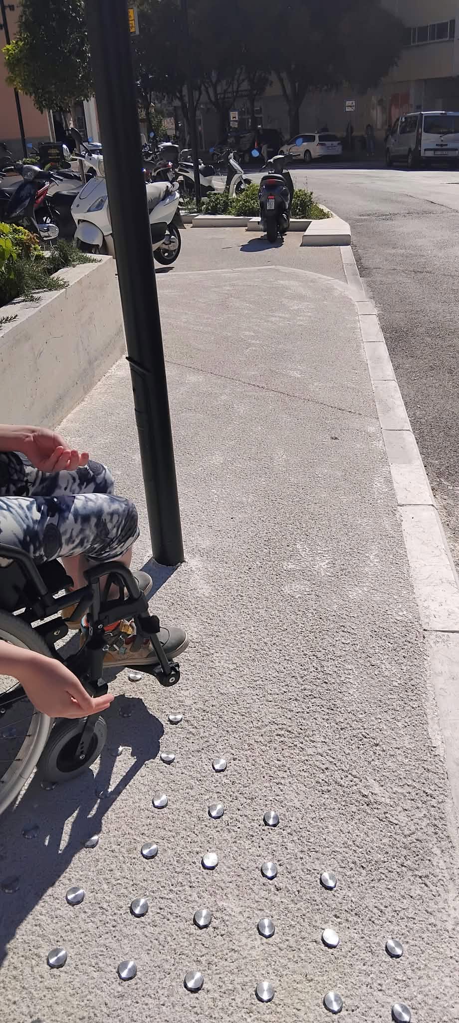 Kolica uz stup na taktilnoj stazi, pogled prema parkingu za motore